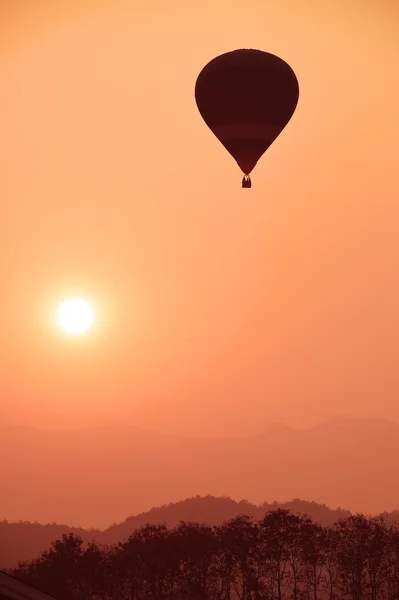 Balão de ar quente colorido está voando ao pôr do sol — Fotografia de Stock