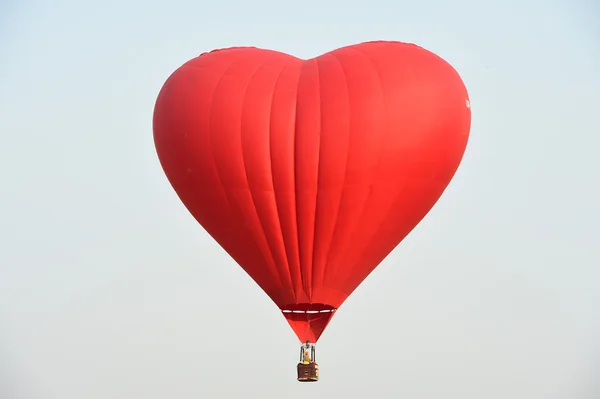 Röd ballong i form av ett hjärta mot den blå himlen — Stockfoto