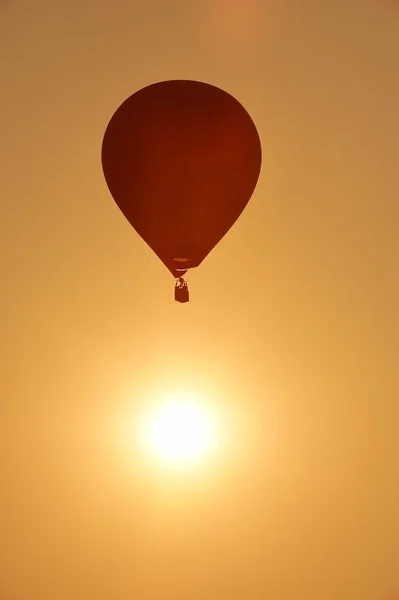 Balão de ar quente colorido está voando ao pôr do sol — Fotografia de Stock