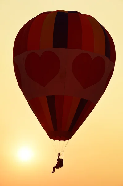 Balão de ar quente colorido está voando ao pôr do sol — Fotografia de Stock