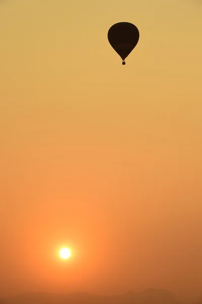 Balão de ar quente colorido está voando ao pôr do sol — Fotografia de Stock