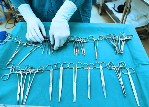 Detalle plano de instrumentos de cirugía esteralizada con una mano agarrando una herramienta —  Fotos de Stock