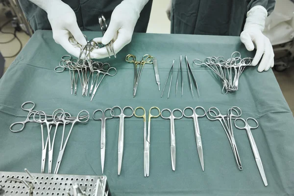 Detalhe tiro de instrumentos de cirurgia esterilizados com uma mão agarrando uma ferramenta — Fotografia de Stock