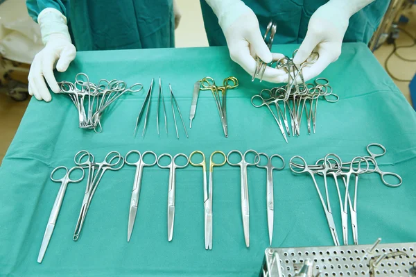 Detalle plano de instrumentos de cirugía esteralizada con una mano agarrando una herramienta —  Fotos de Stock