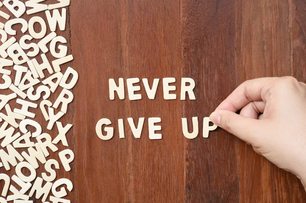 Palavra nunca desistir feito com letras de madeira bloco — Fotografia de Stock
