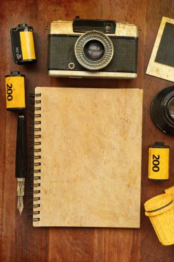Boş defter ile Foto film ve ahşap arka plan üzerinde kamera