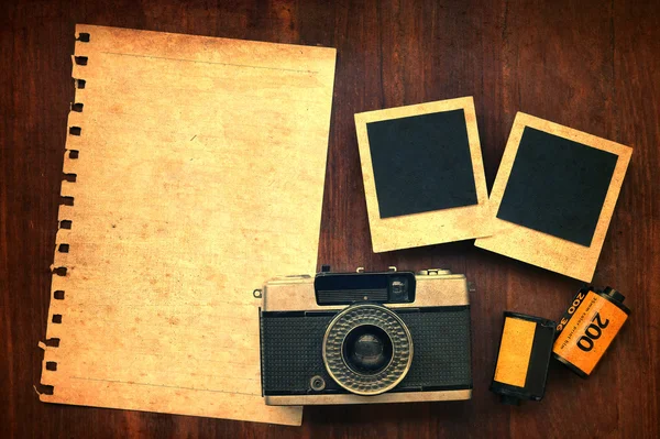 Papel em branco com filme fotográfico, molduras para fotos e câmera em fundo de madeira — Fotografia de Stock