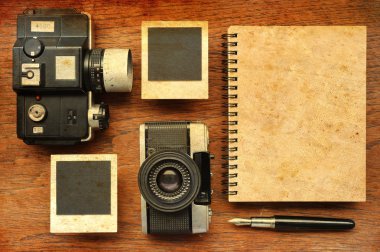 Boş defter kalem, fotoğraf çerçeveleri ve ahşap arka plan üzerinde kamera ile