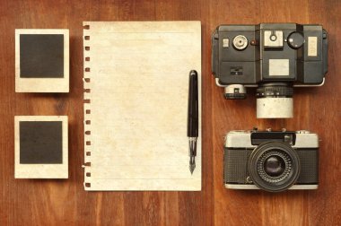 Boş kağıt kalem, fotoğraf çerçeveleri ve ahşap arka plan üzerinde kamera ile