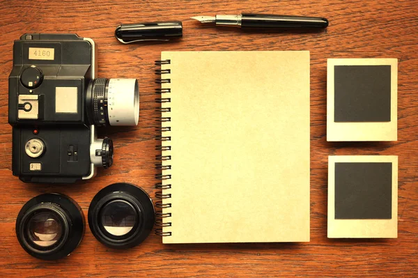 Leeres Notizbuch mit Stift, Fotorahmen und Kamera auf Holzgrund — Stockfoto