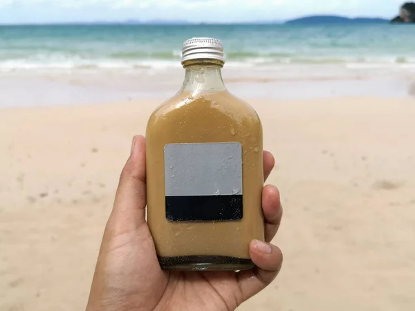 Закройте Руку Держа Бутылку Кофе Фоне Моря Песка — стоковое фото