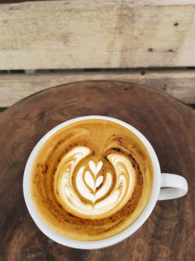 Ahşap arka planda bir fincan latte sanat kahvesi.                                                                                                                                                                     