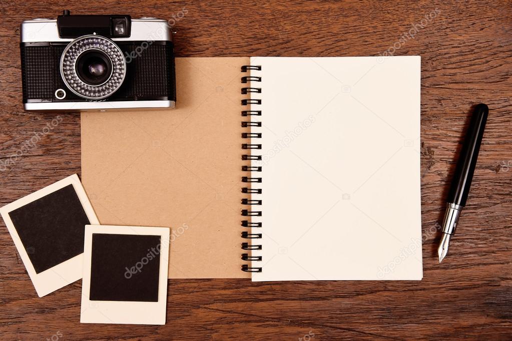 Blank notebook with pen, photo frames and camera
