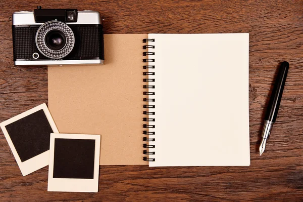 Caderno em branco com caneta, molduras para fotos e câmera — Fotografia de Stock