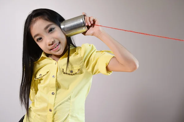 Little girl using a can as telephone — Stock Photo, Image