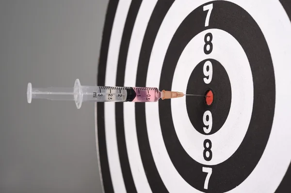 Syringe in dart board on gray background — Stock Photo, Image