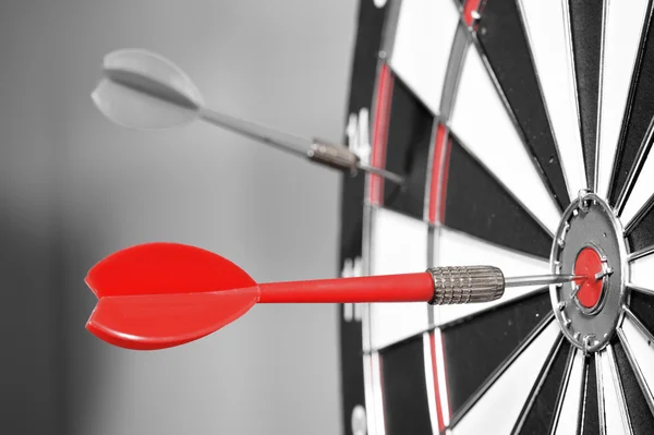 Dartboard with red darts on gray background — Stock Photo, Image