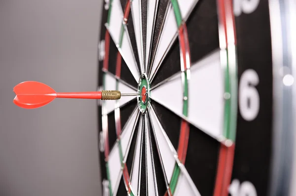 Dartboard com dardos vermelhos no fundo cinza — Fotografia de Stock