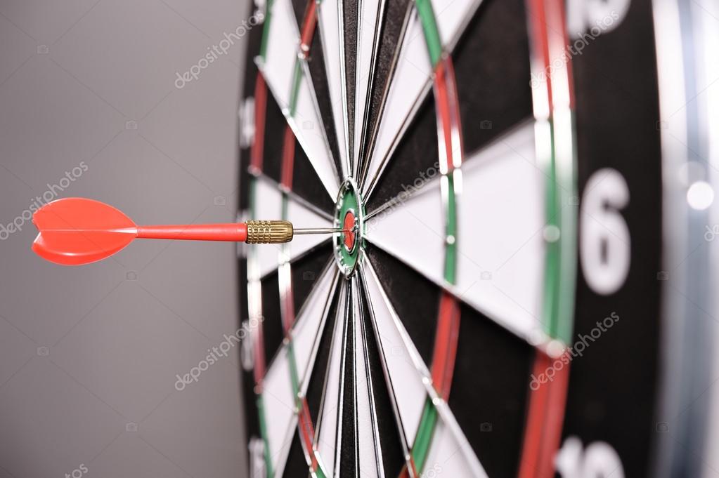 Dartboard with red darts on gray background