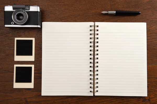Prázdný zápisník s perem, fotorámečky a fotoaparát — Stock fotografie