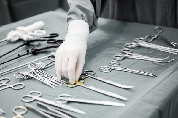 Detail shot of steralized surgery instruments with a hand grabbing a tool