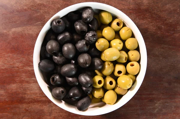 Olives vertes et noires dans un bol blanc — Photo