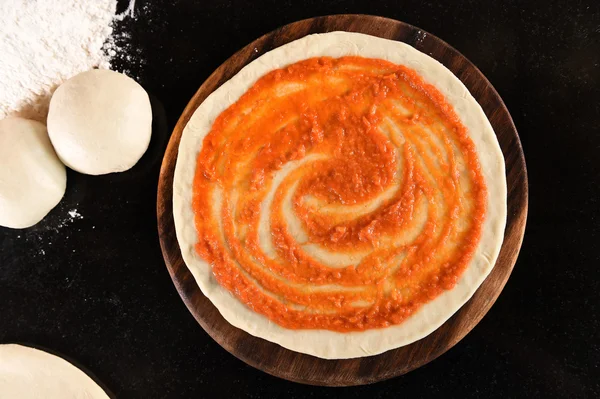 Dodając sos pomidorowy do pizzy podstawy — Zdjęcie stockowe