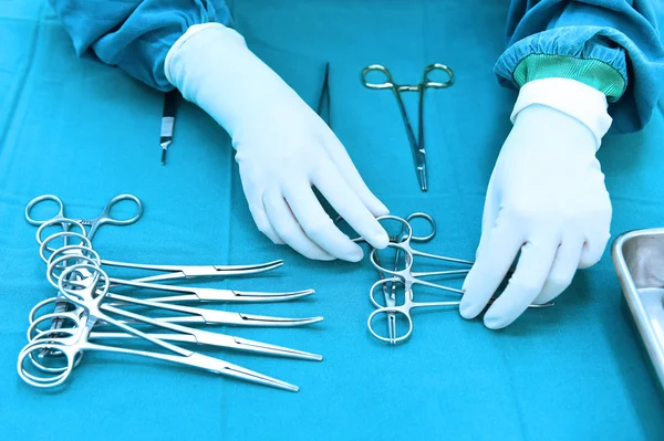 Prise de vue détaillée d'instruments chirurgicaux stérilisés avec une main saisissant un outil — Photo