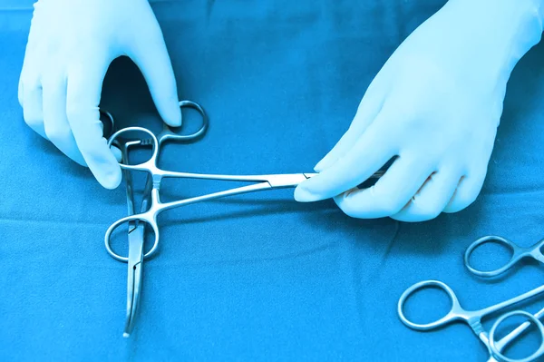 Prise de vue détaillée d'instruments chirurgicaux stérilisés avec une main saisissant un outil — Photo