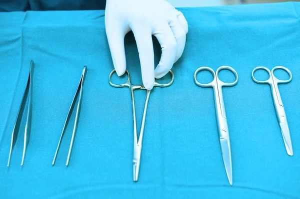 Detalle plano de instrumentos de cirugía esteralizada con una mano agarrando una herramienta — Foto de Stock