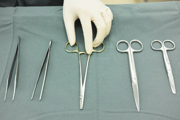 Detailaufnahme steriler Operationsinstrumente mit einer Hand, die ein Werkzeug ergreift — Stockfoto