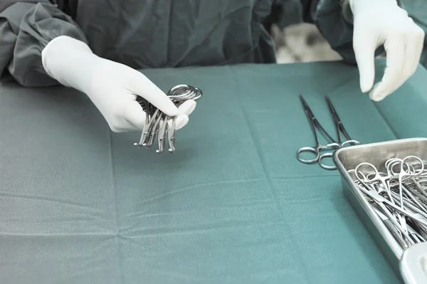 Detalhe tiro de instrumentos de cirurgia esterilizados com uma mão agarrando uma ferramenta — Fotografia de Stock