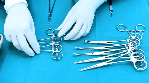 Detalle plano de instrumentos de cirugía esteralizada con una mano agarrando una herramienta —  Fotos de Stock