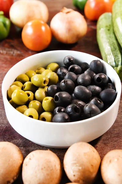 Olives vertes et noires dans un bol blanc et ingrédients pour pizza — Photo