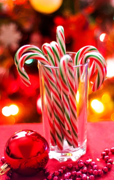 Sweet canes in the glass on the background of the Christmas tree — Stock Photo, Image