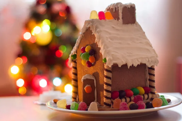 Casa de jengibre en el plato en el fondo de las luces de Navidad —  Fotos de Stock