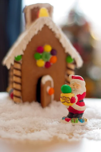 The figure of Santa Claus in the background of a gingerbread house,which holds the candy — Stock Photo, Image