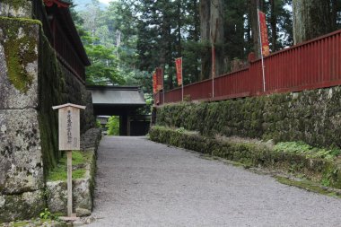 Japon Shinto Budist tapınağında taş duvar ve kırmızı çitlerle kaplı boş çakıl yolu.