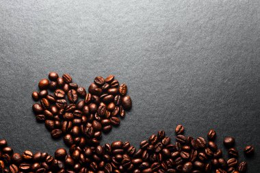 Kahve çekirdekleri gri arka planda kalp şekli oluşturur.