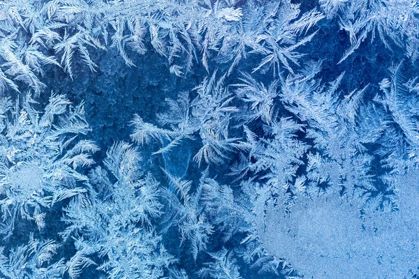Frostiges Wintermuster an einem Fensterglas Stockbild
