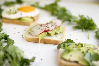 Çeşitli kahvaltı sandviçleri, abur cuburlar, avokado, sahanda yumurta, domates, turp. Hafif bir arkaplan pankartıyla