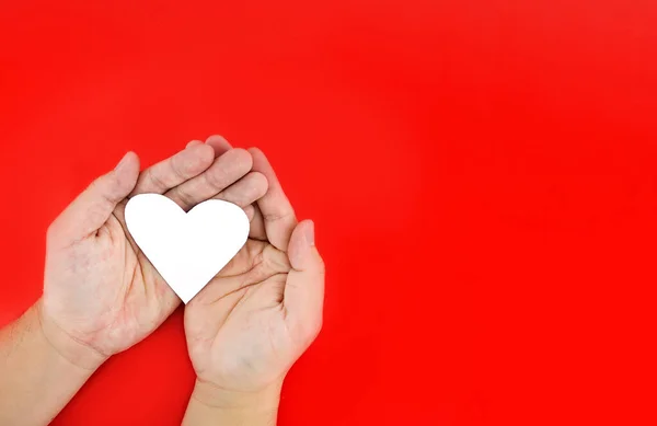 With both hands holding a white heart On a red background