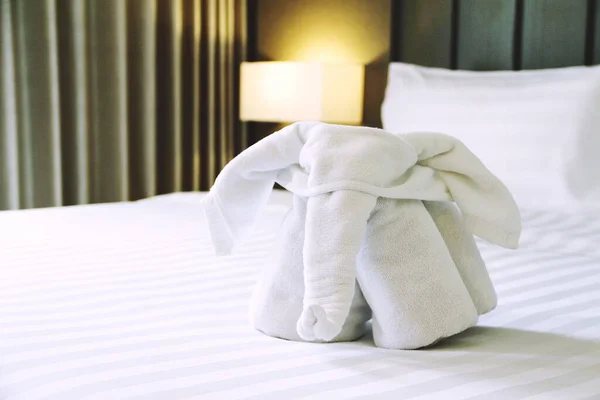 Hoş geldin beyaz fil havlusu beyaz yatakta sunulan otel odasında.