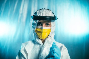 Tam güvenlikli anti virüs teçhizatlı kadın doğrudan kameraya bakıyor.