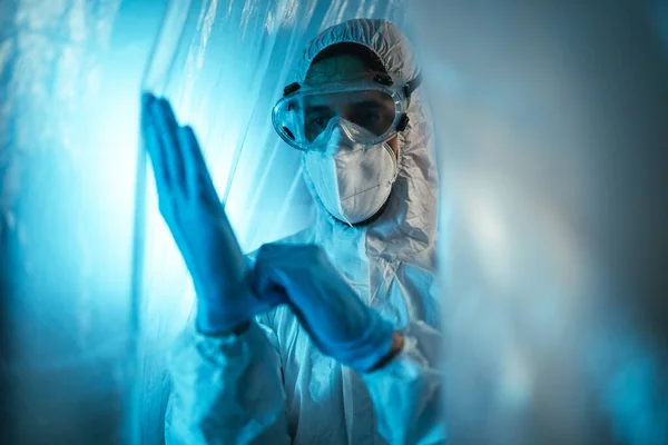 Photo of a man equipped in full safety clothes behind plastic curtain