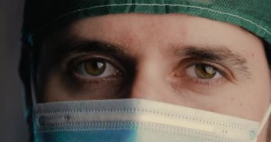 Tıbbi maske takan bir adamın kameraya baktığı görüntüler.