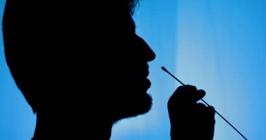 Burnunda pamuk çubuğu olan erkek siluetinin yan görüntüsü.