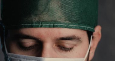 Tıbbi maske takan bir adamın kameraya baktığı görüntüler.