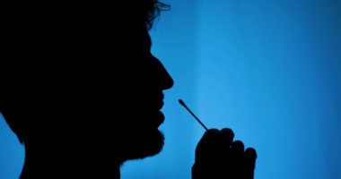 Burnunda pamuk çubuğu olan bir adamın yan görüntüsü.