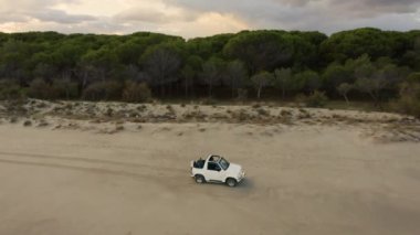 Gün batımında plajda araba sürüyor. 